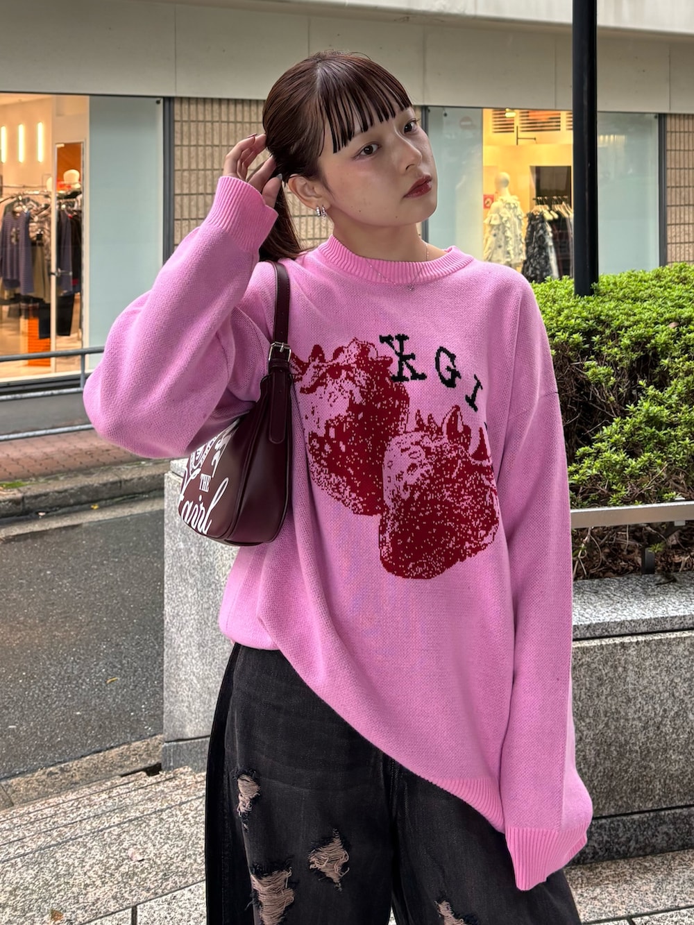 ピンク系のニット/セーター、ブラック系のデニムパンツ、レッド系のハンドバッグを着用したレディースの秋コーディネートの4枚目の写真