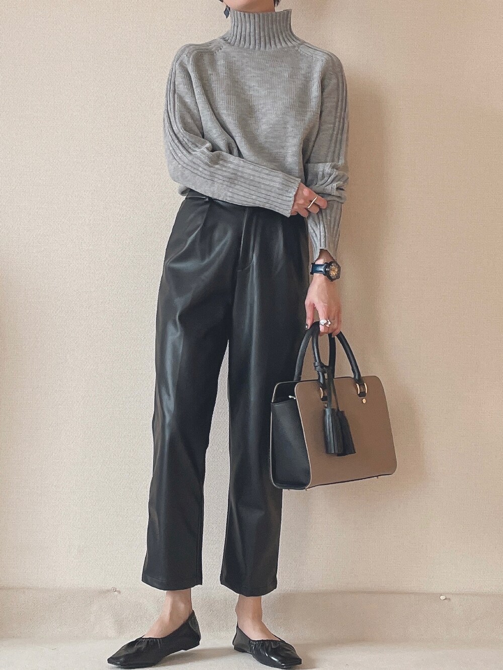 グレー系のニット/セーター、ブラック系のその他パンツ、ベージュ系のビジネスバッグを着用したレディースの秋コーディネートの2枚目の写真