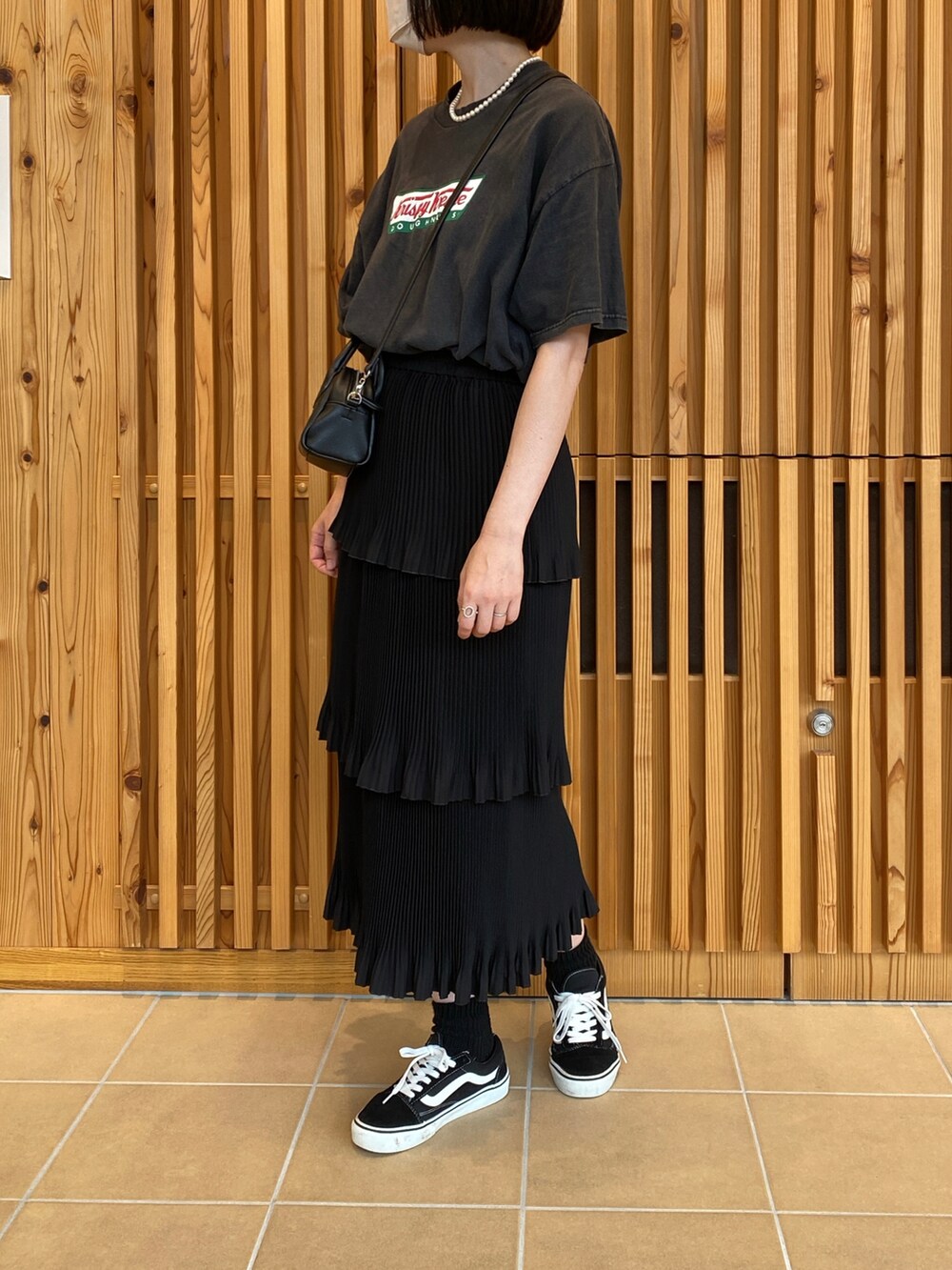 ブラック系のTシャツ/カットソー、ブラック系のスカート、ブラック系のスニーカーを着用したレディースの秋コーディネートの2枚目の写真