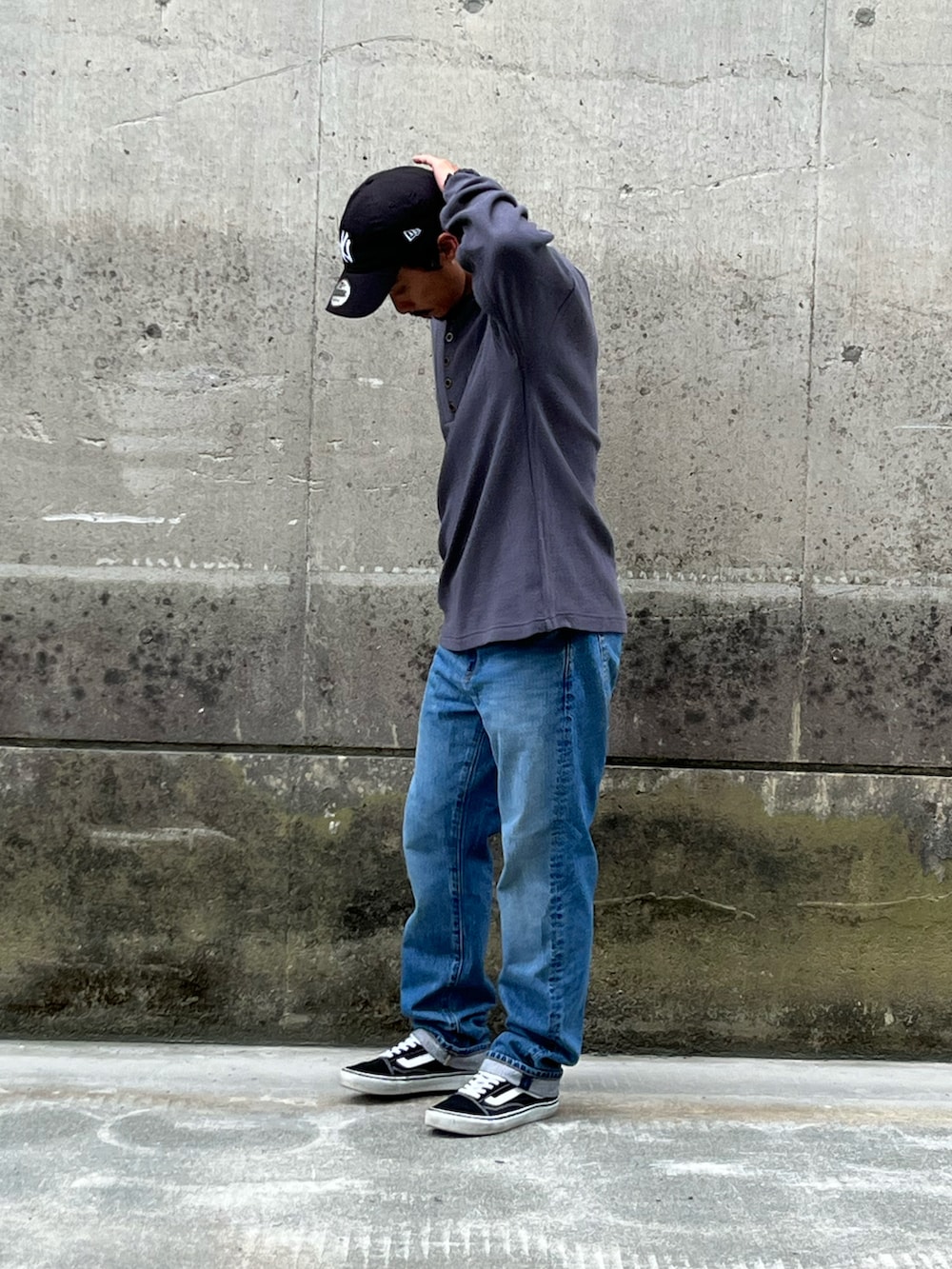 グレー系のTシャツ/カットソー、ブルー系のデニムパンツ、ブラック系のスニーカーを着用したメンズの秋コーディネートの2枚目の写真