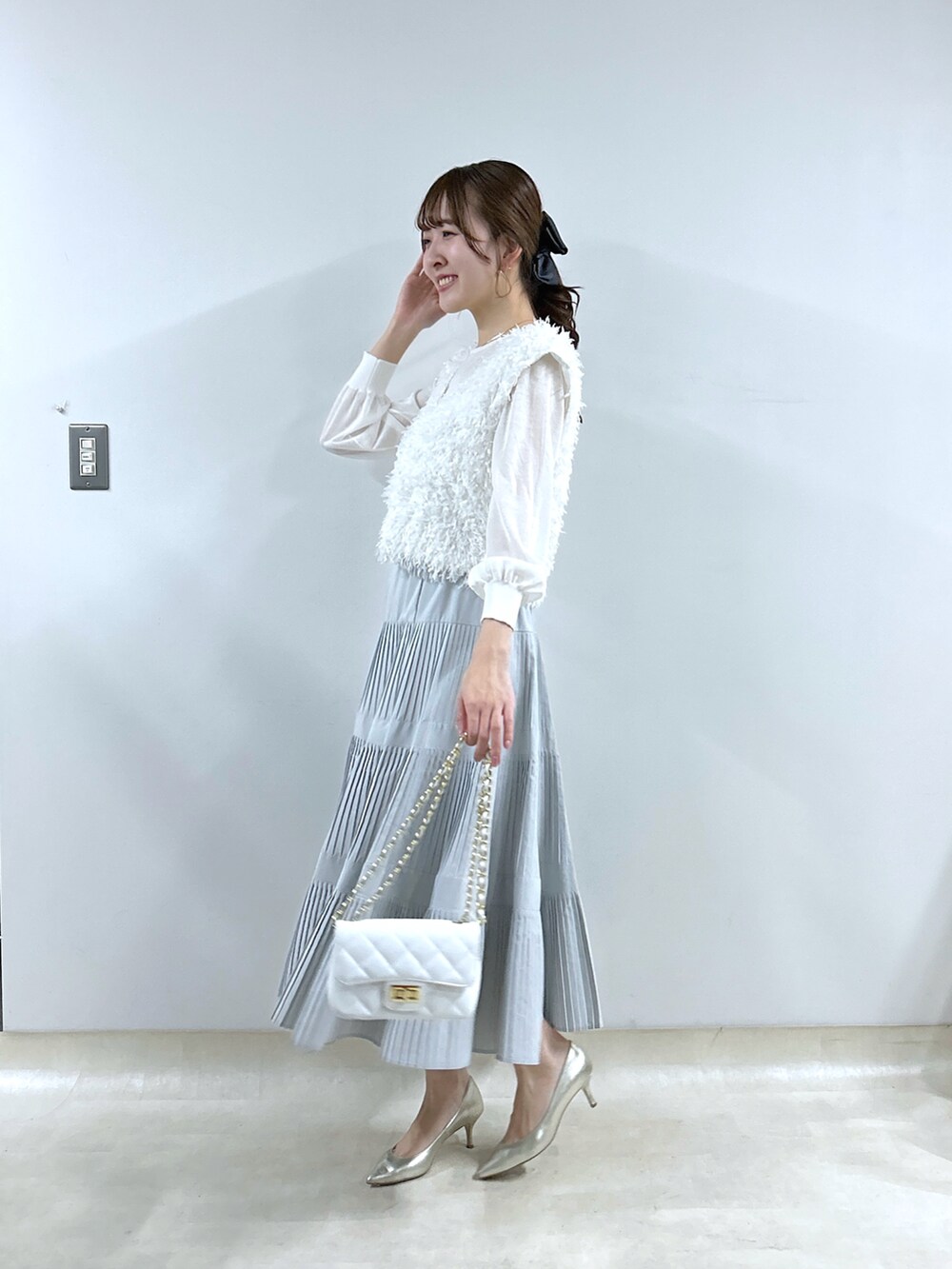 ホワイト系のシャツ/ブラウス、グレー系のスカート、ホワイト系のニット/セーターを着用したレディースの冬コーディネートの2枚目の写真