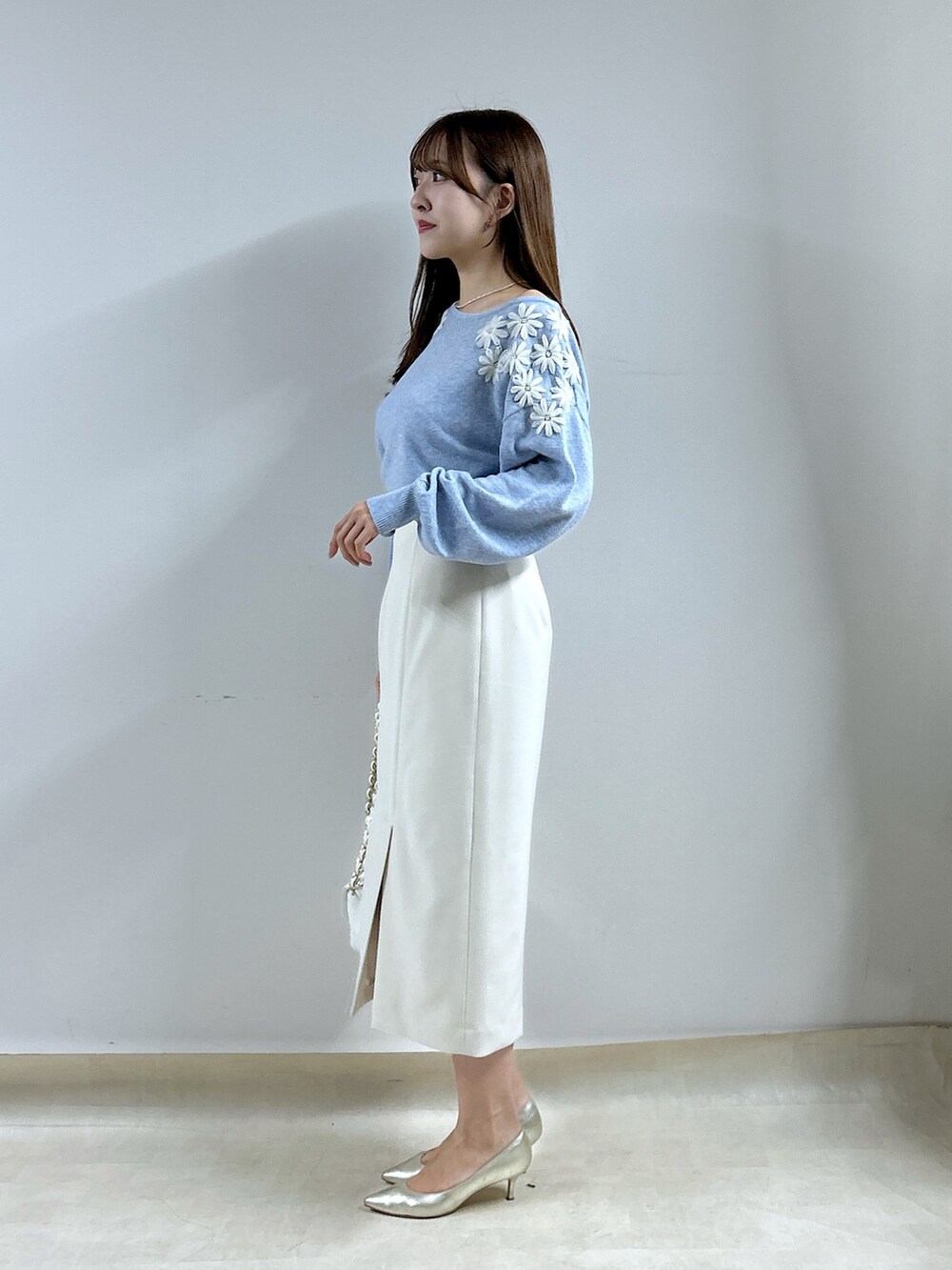 ブルー系のニット/セーター、ホワイト系のスカートを着用したレディースの秋コーディネートの2枚目の写真