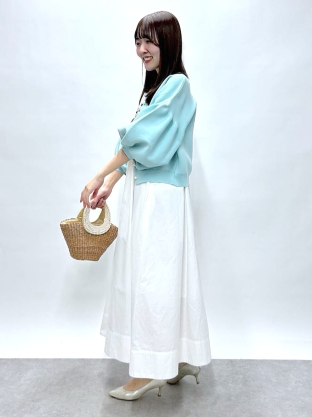 ベージュ系のかごバッグ、ホワイト系のワンピース、ブルー系のカーディガン/ボレロを着用したレディースの春コーディネートの2枚目の写真