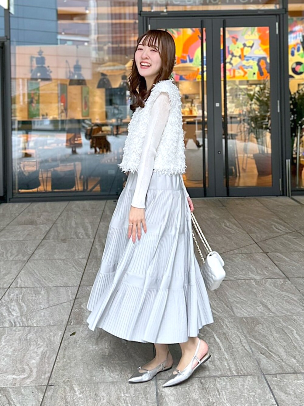 ホワイト系のシャツ/ブラウス、グレー系のスカート、ホワイト系のニット/セーターを着用したレディースの春コーディネートの2枚目の写真