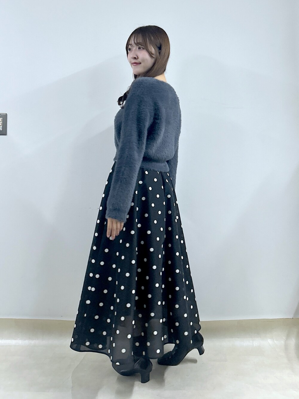 グレー系のカーディガン/ボレロ、ブルー系のスカートを着用したレディースの秋コーディネートの2枚目の写真