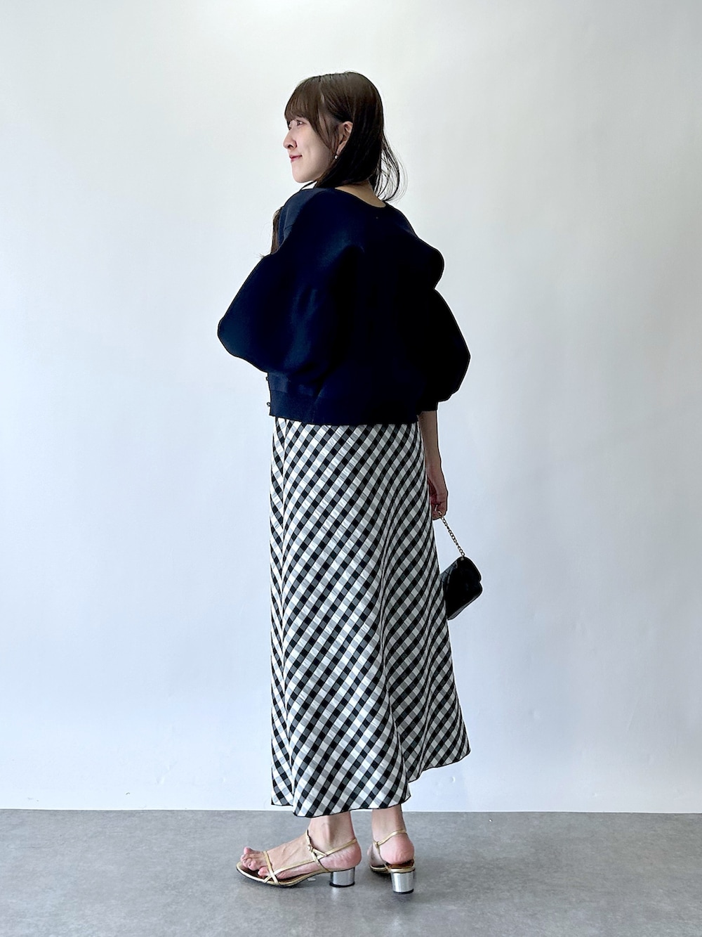 ブラック系のスカート、ブルー系のカーディガン/ボレロ、ホワイト系のタンクトップを着用したレディースの夏コーディネートの4枚目の写真