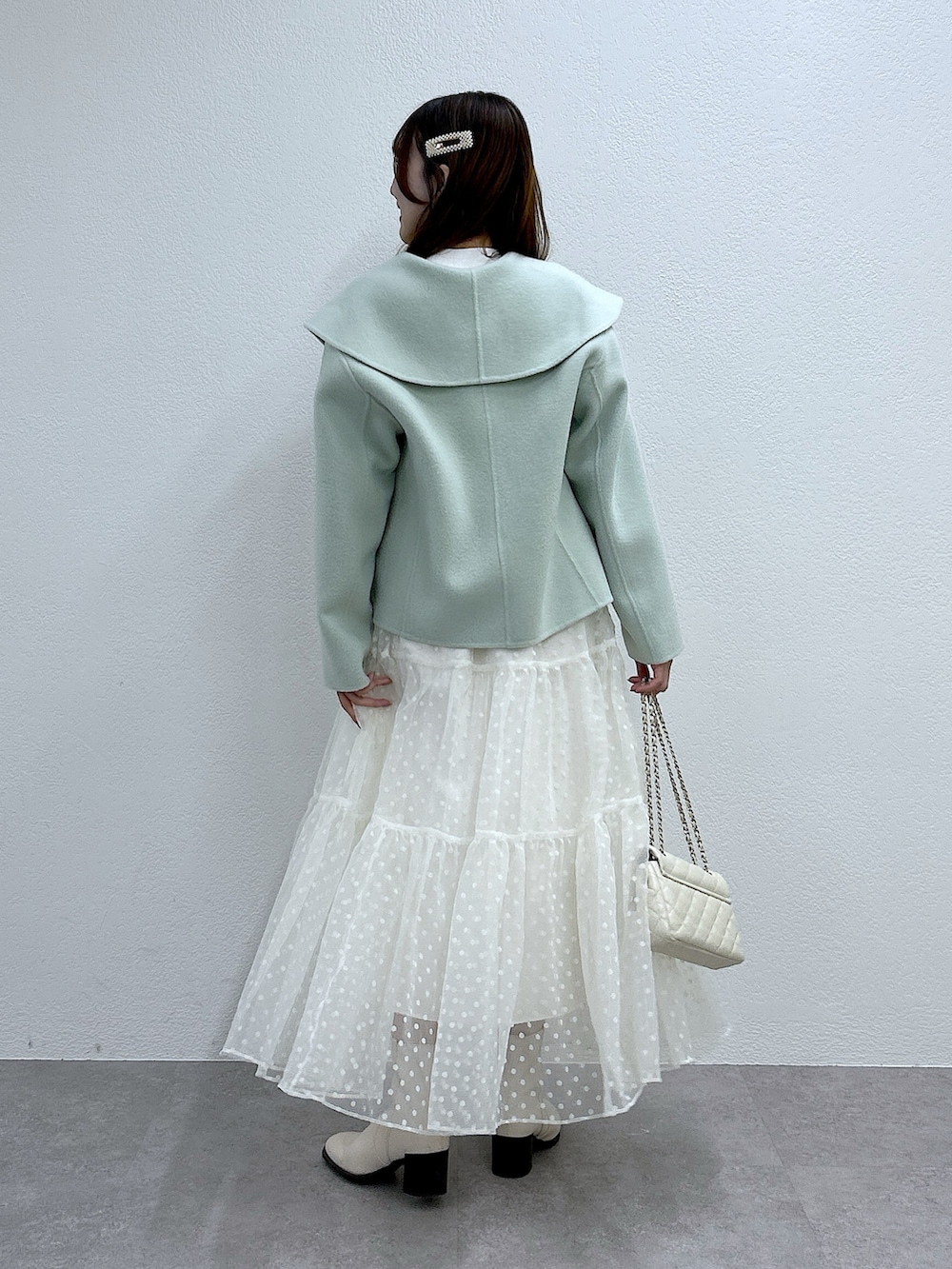 グリーン系のその他アウター、ホワイト系のニット/セーター、ホワイト系のスカートを着用したレディースの秋コーディネートの3枚目の写真