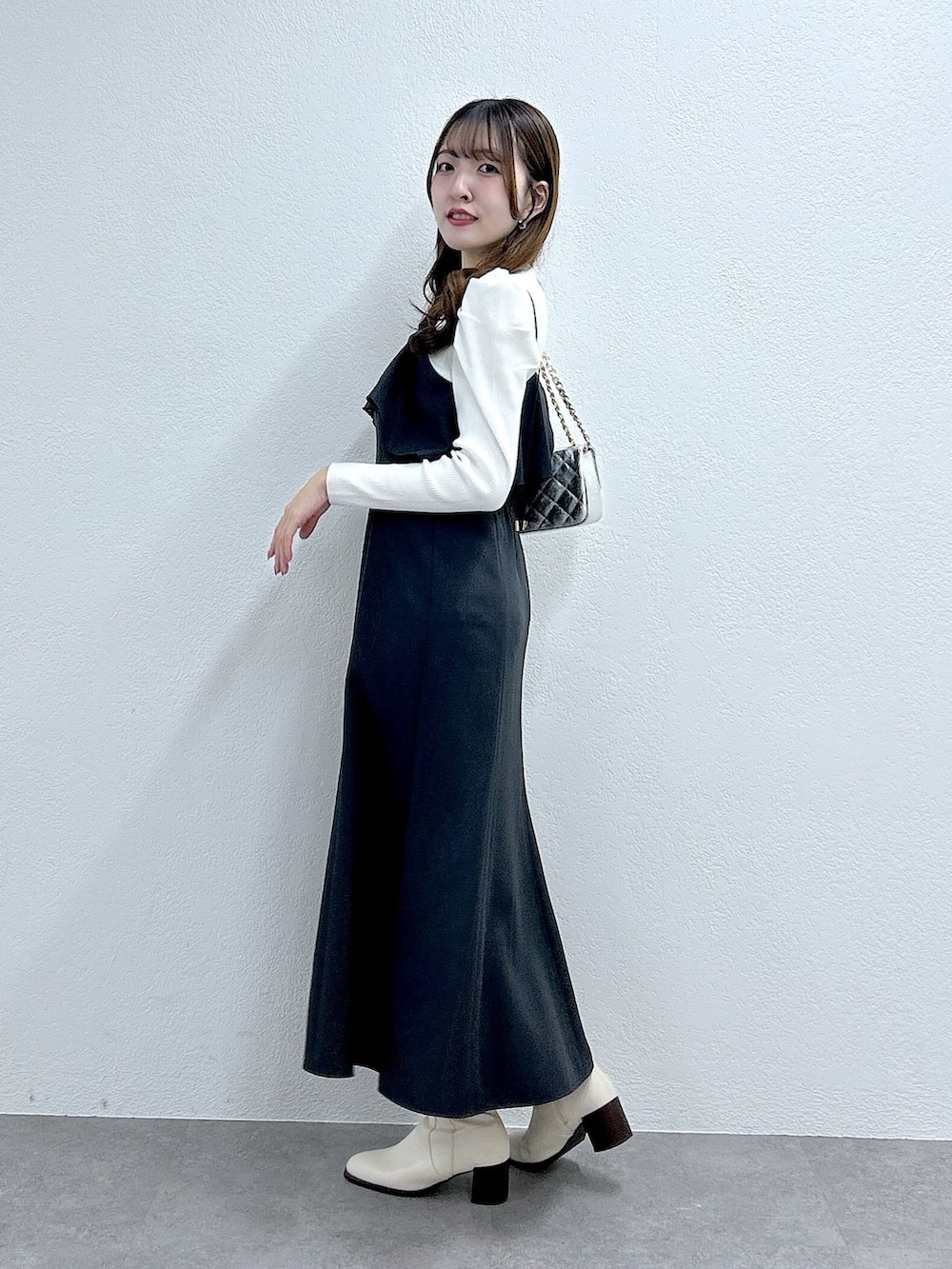 グレー系のワンピース、ホワイト系のニット/セーターを着用したレディースの秋コーディネートの3枚目の写真