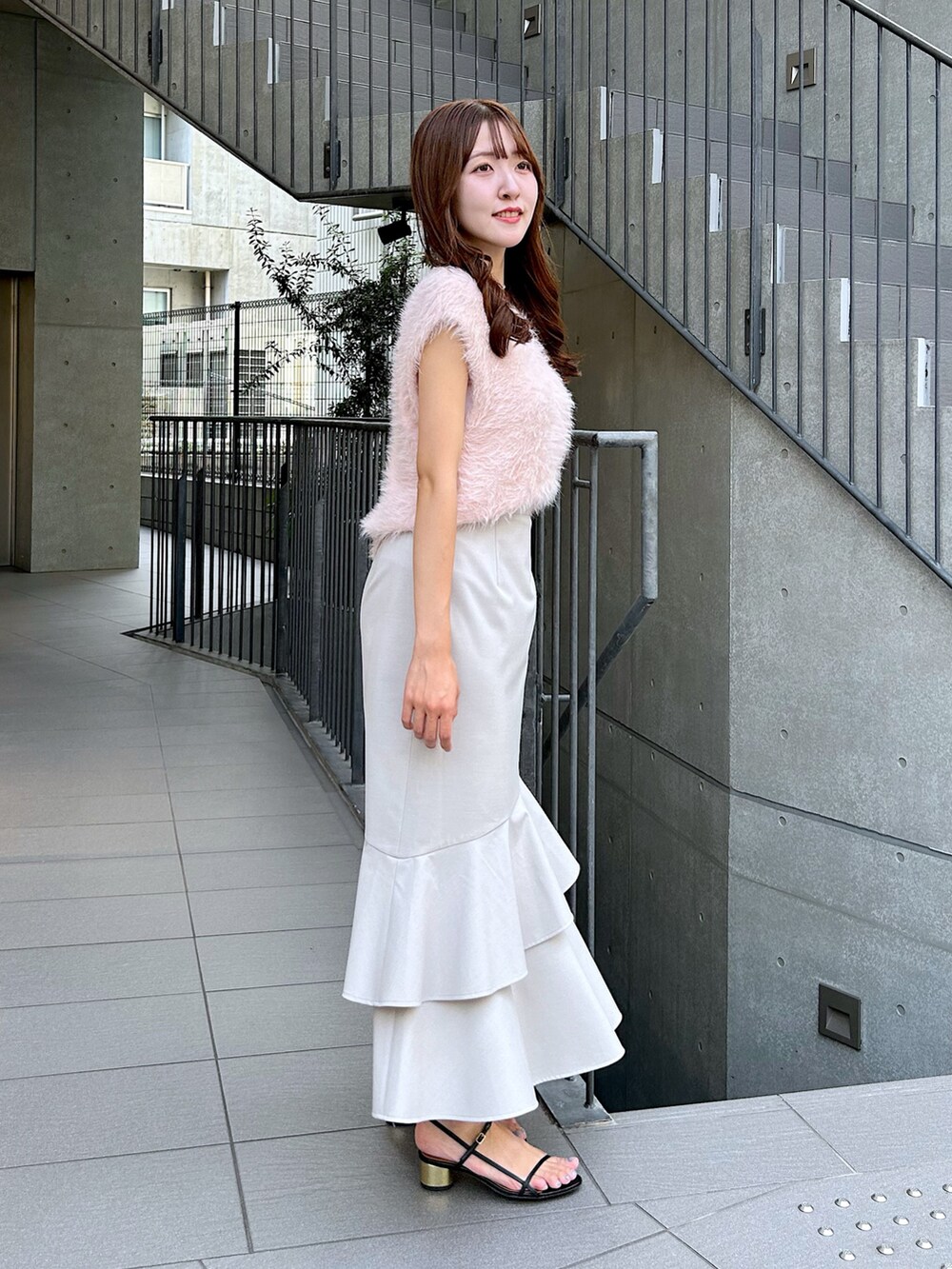 ピンク系のベスト、ベージュ系のスカートを着用したレディースの夏コーディネートの2枚目の写真