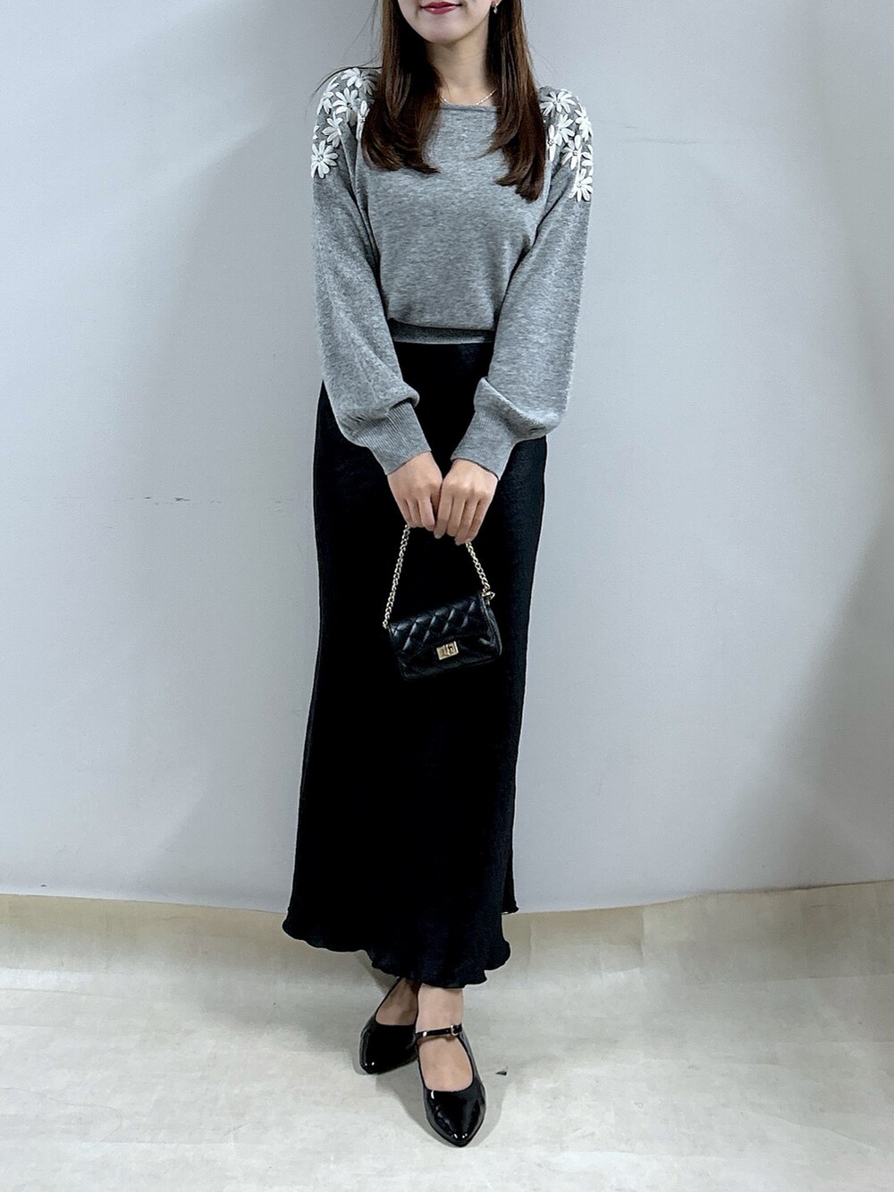 グレー系のニット/セーター、ブラック系のスカートを着用したレディースの秋コーディネートの4枚目の写真