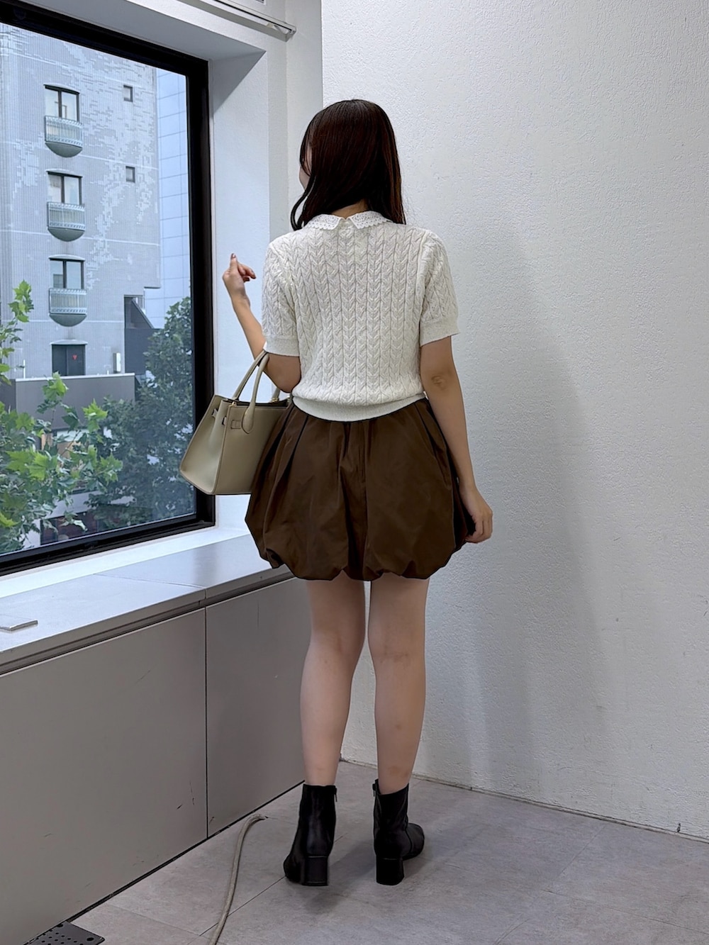 ホワイト系のニット/セーター、ブラウン系のスカート、グレー系のトートバッグを着用したレディースの夏コーディネートの3枚目の写真