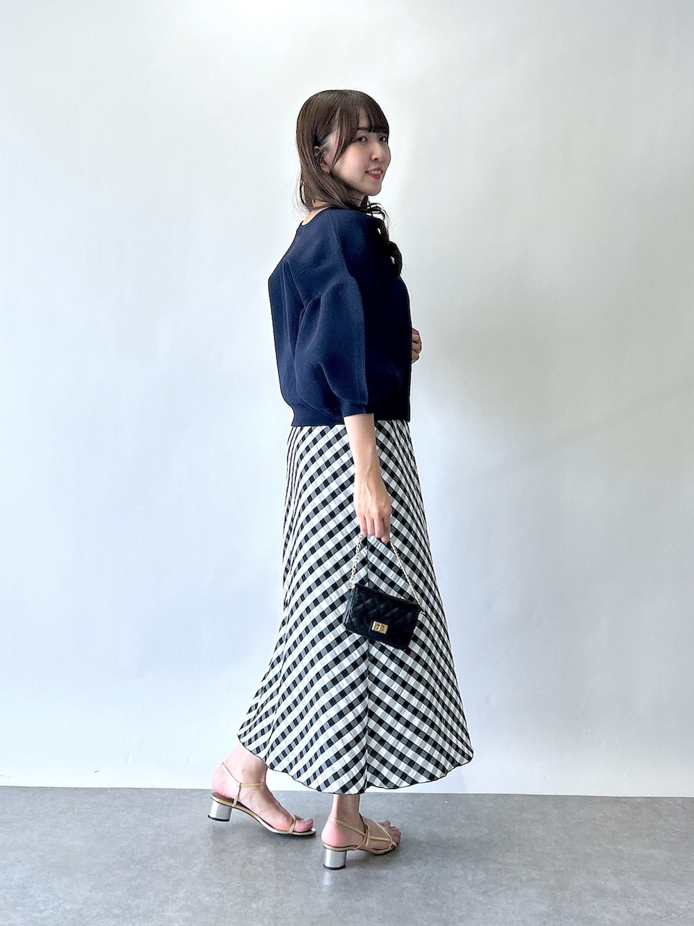 ブラック系のスカート、ブルー系のカーディガン/ボレロ、ホワイト系のタンクトップを着用したレディースの夏コーディネートの3枚目の写真