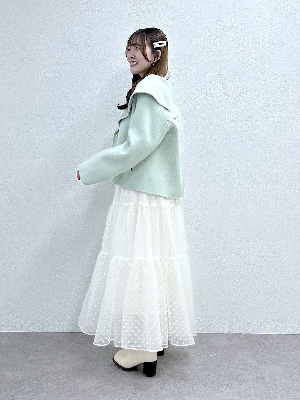 グリーン系のその他アウター、ホワイト系のニット/セーター、ホワイト系のスカートを着用したレディースの秋コーディネートの2枚目の写真