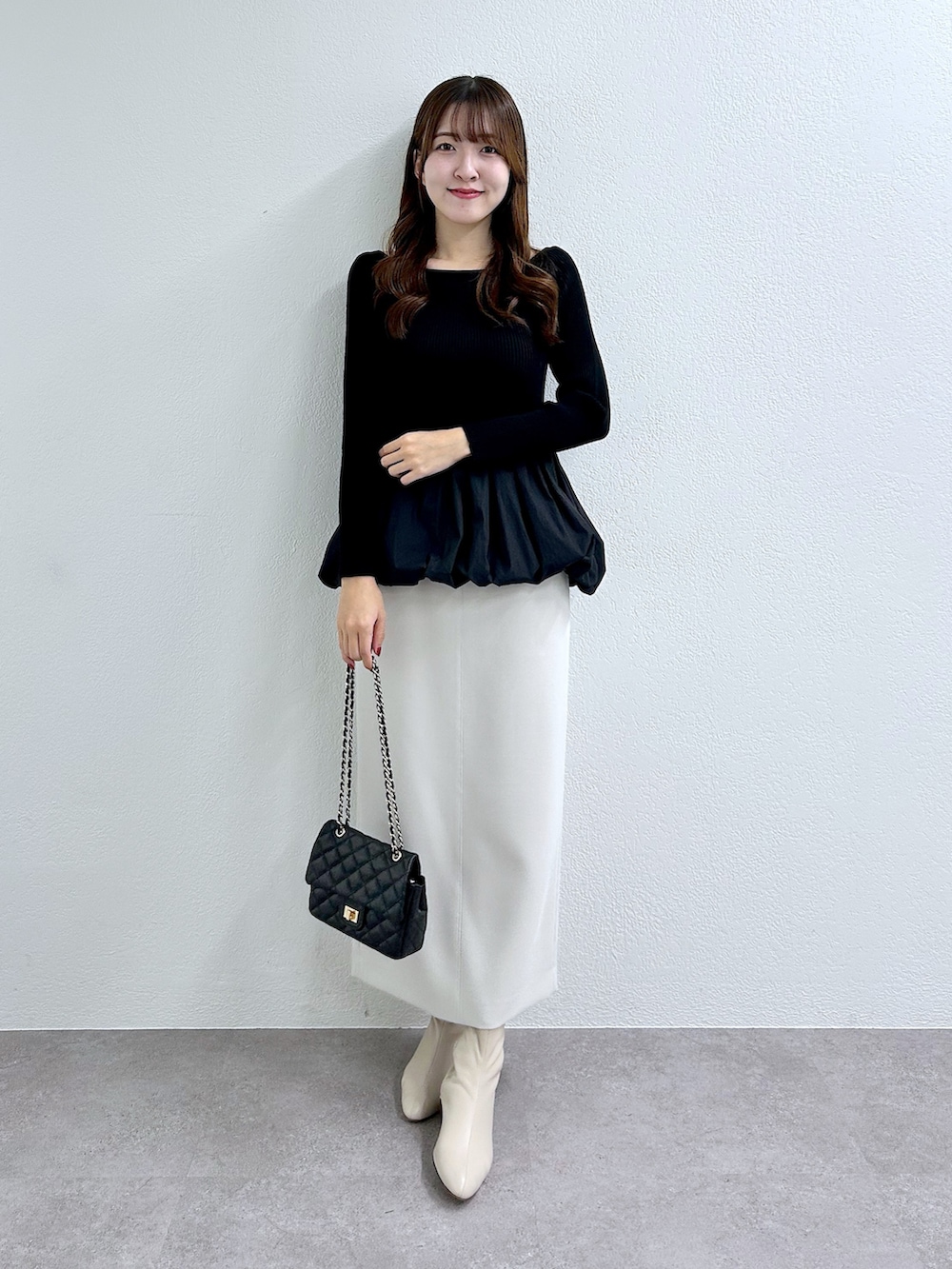 ブラック系のニット/セーター、グレー系のスカートを着用したレディースの秋コーディネートの2枚目の写真