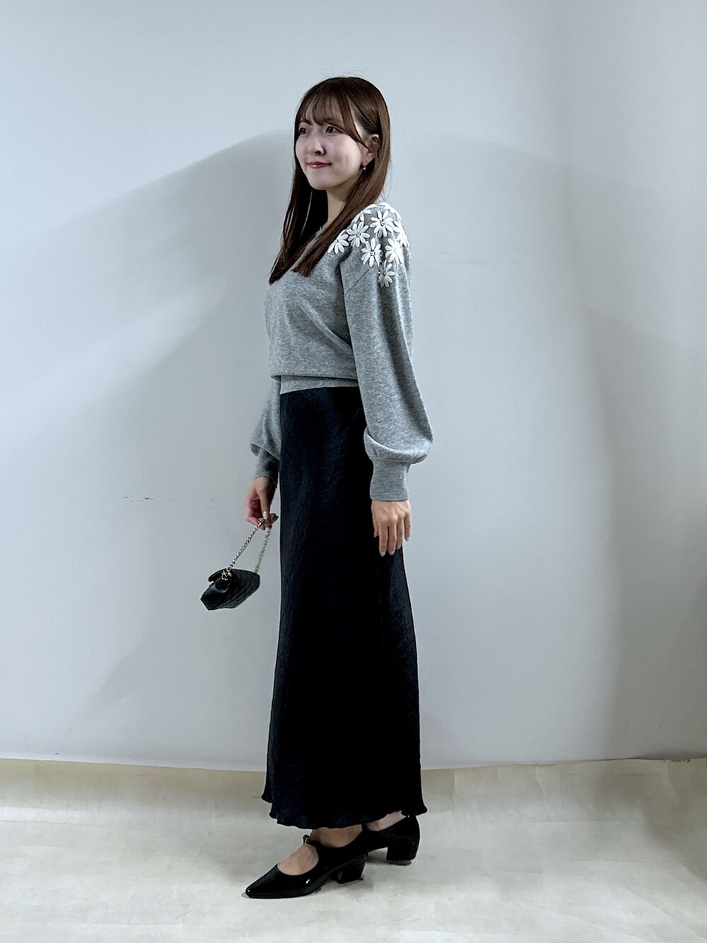 グレー系のニット/セーター、ブラック系のスカートを着用したレディースの秋コーディネートの2枚目の写真