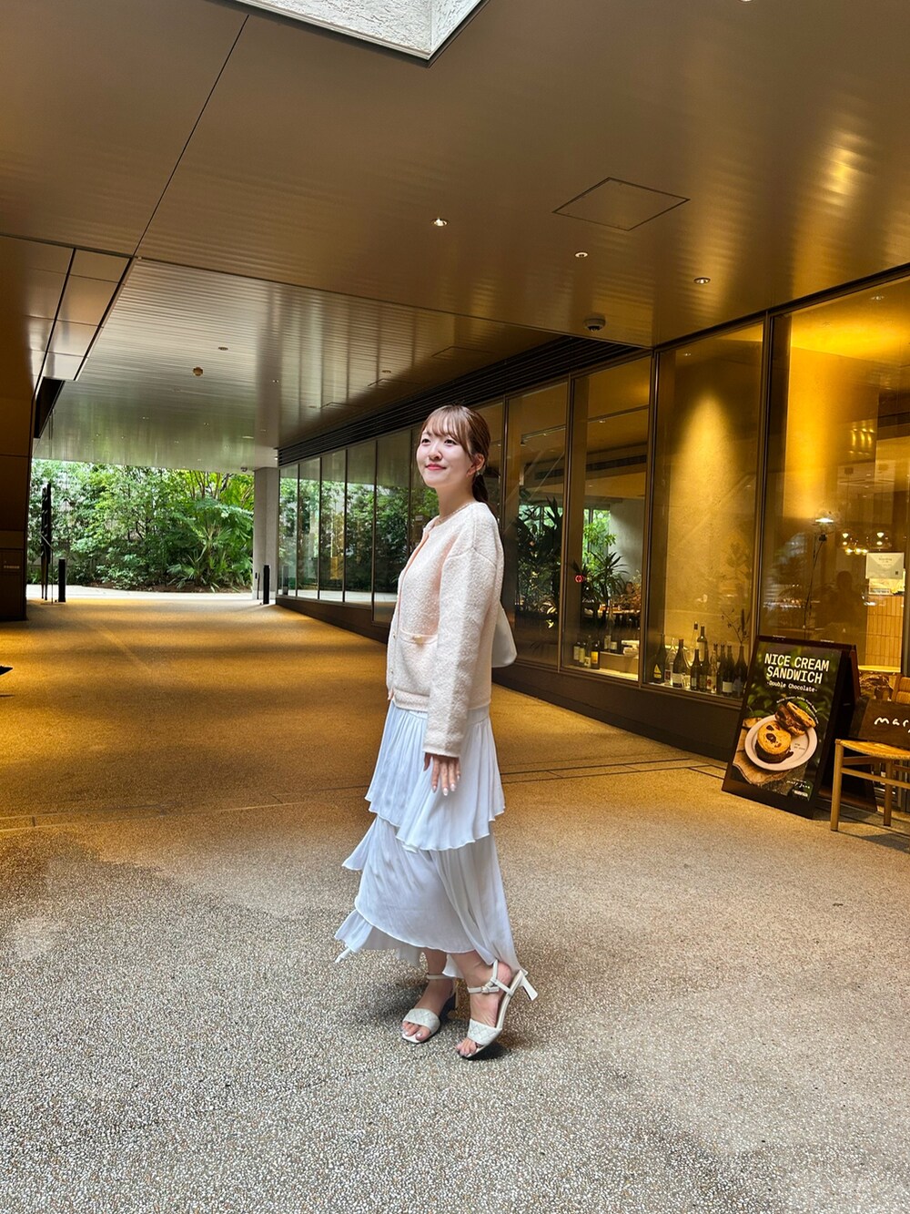 ピンク系のノーカラージャケット、ホワイト系のスカート、ホワイト系のサンダルを着用したレディースの秋コーディネートの4枚目の写真
