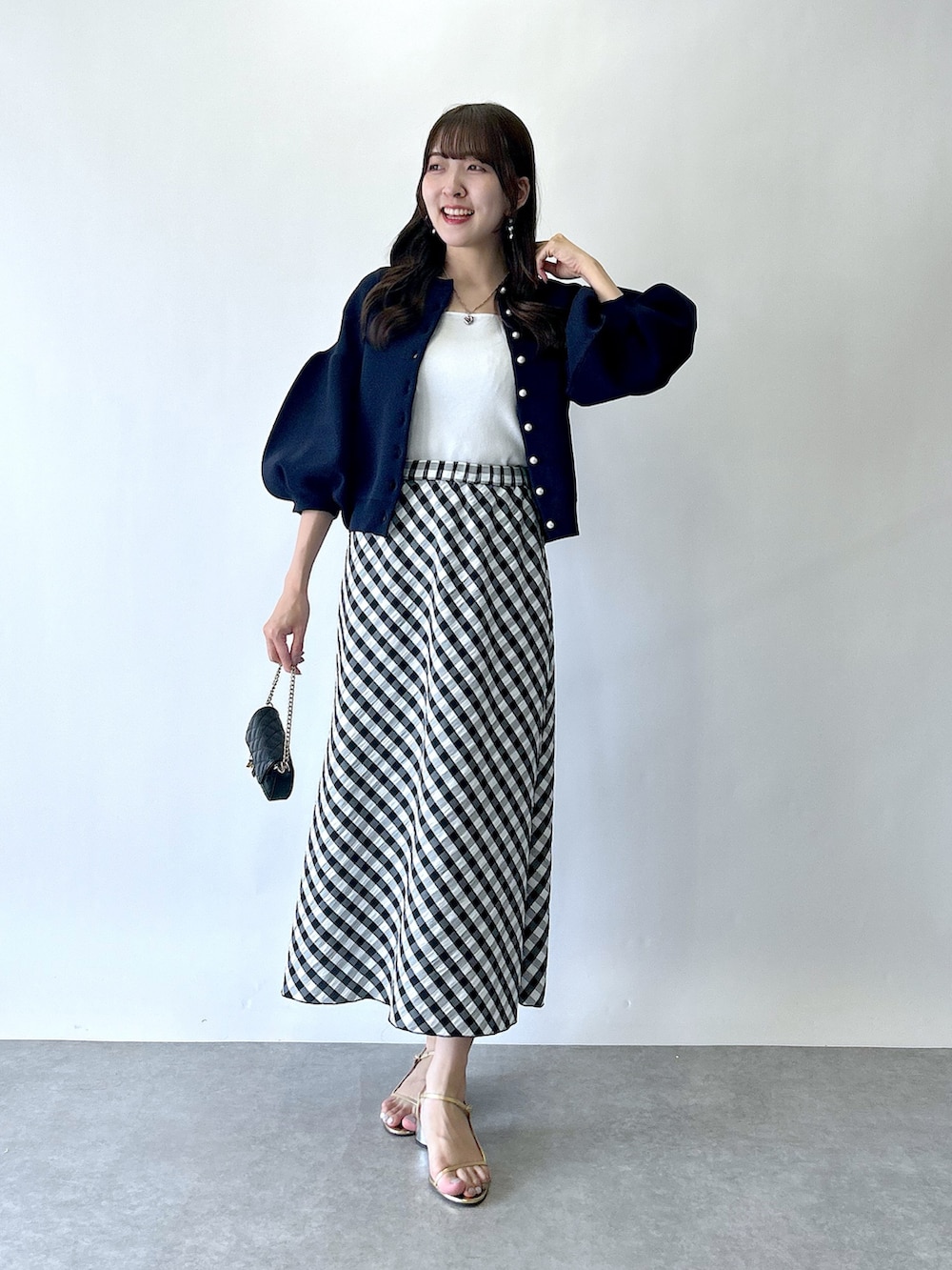 ブラック系のスカート、ブルー系のカーディガン/ボレロ、ホワイト系のタンクトップを着用したレディースの夏コーディネートの5枚目の写真