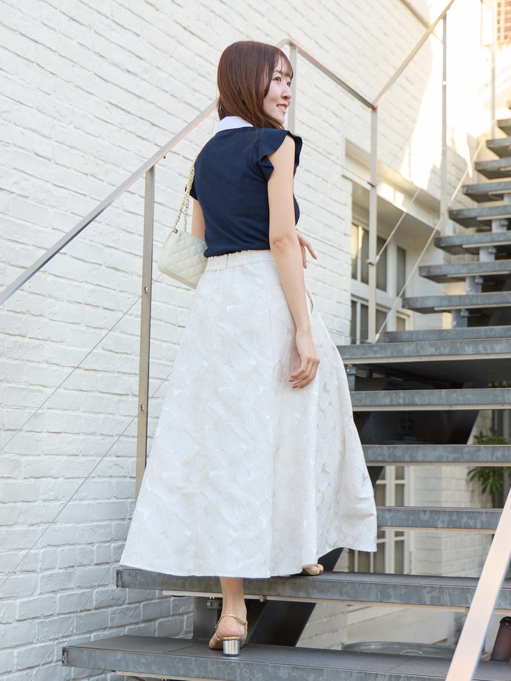 ブルー系のニット/セーター、ホワイト系のスカートを着用したレディースの春コーディネートの4枚目の写真