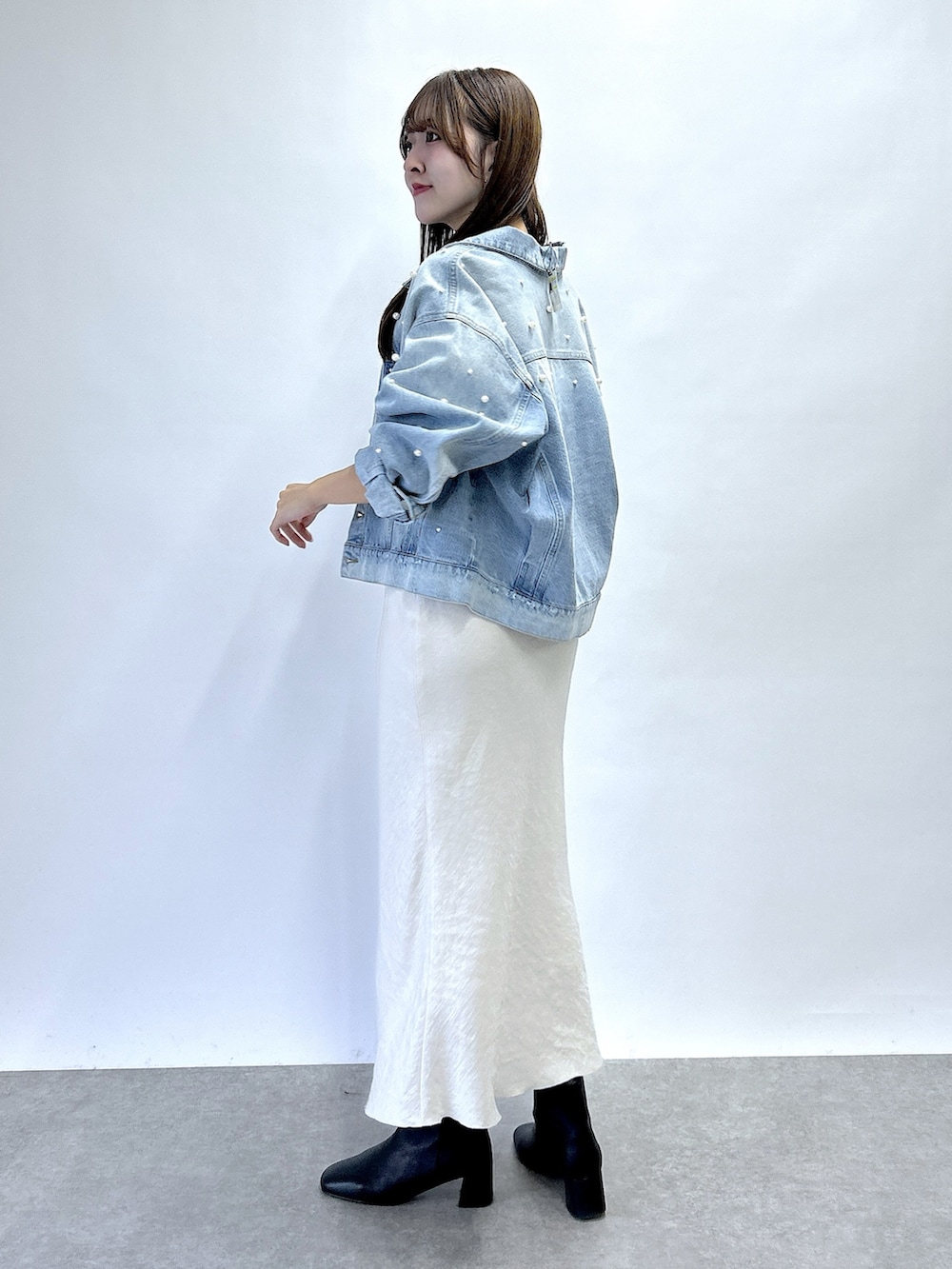 ブルー系のデニムジャケット、ブルー系のニット/セーター、グレー系のスカートを着用したレディースの秋コーディネートの2枚目の写真