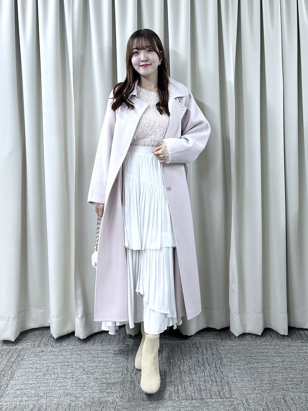 ピンク系のステンカラーコート、ピンク系のニット/セーター、ホワイト系のスカートを着用したレディースの秋コーディネートの3枚目の写真