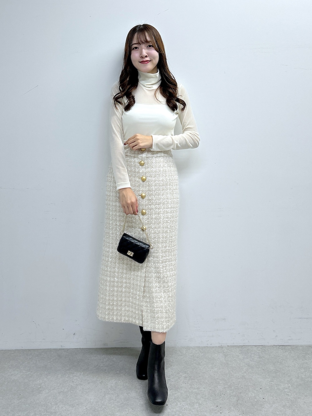 ホワイト系のTシャツ/カットソー、ベージュ系のスカート、ブラック系のブーツを着用したレディースの秋コーディネートの4枚目の写真