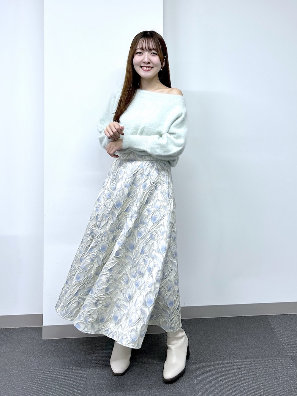 グリーン系のニット/セーター、ブルー系のスカートを着用したレディースの秋コーディネートの3枚目の写真