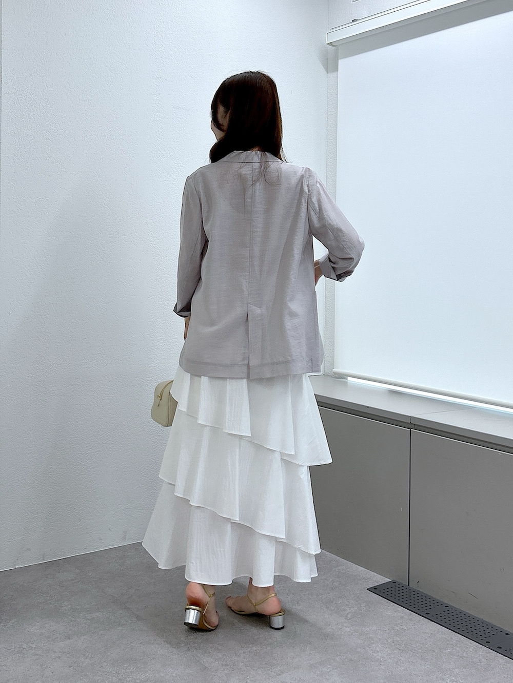 ベージュ系のニット/セーター、ベージュ系のテーラードジャケット、ホワイト系のスカートを着用したレディースの春コーディネートの4枚目の写真