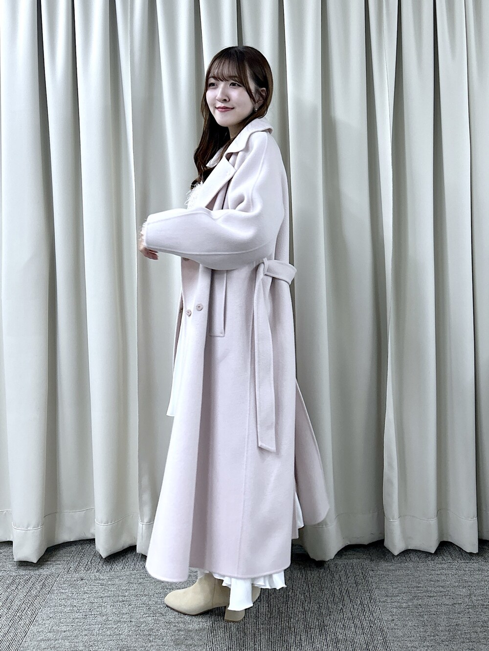 ピンク系のステンカラーコート、ピンク系のニット/セーター、ホワイト系のスカートを着用したレディースの秋コーディネートの2枚目の写真