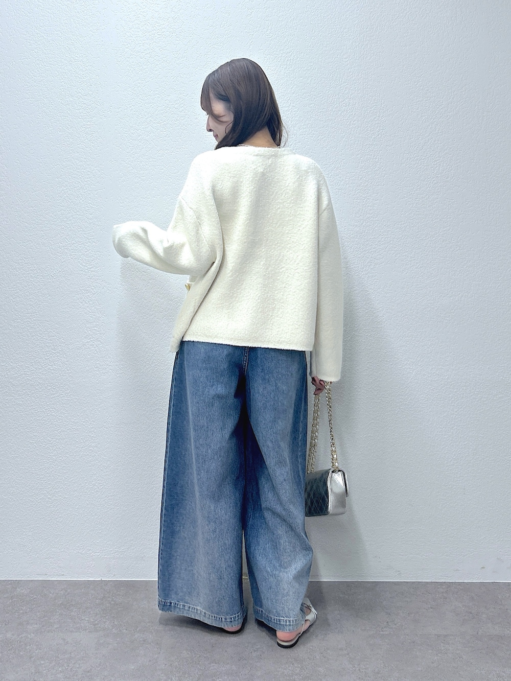 ホワイト系のノーカラージャケット、ブルー系のデニムパンツ、ホワイト系のキャミソールを着用したレディースの秋コーディネートの3枚目の写真