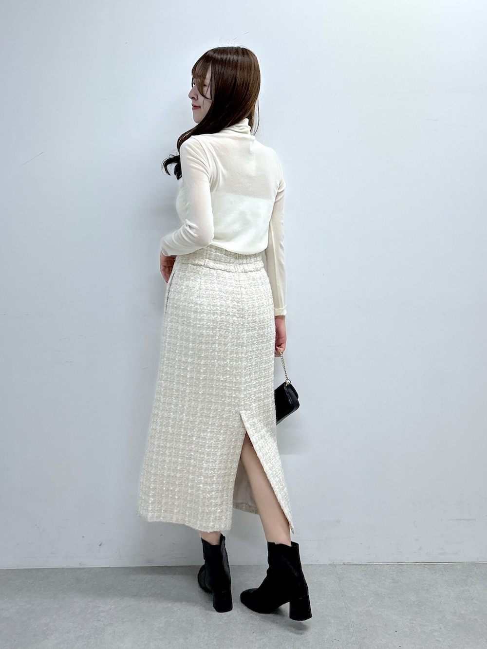 ホワイト系のTシャツ/カットソー、ベージュ系のスカート、ブラック系のブーツを着用したレディースの秋コーディネートの3枚目の写真