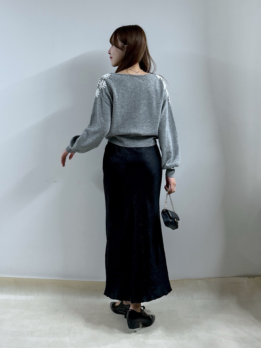 グレー系のニット/セーター、ブラック系のスカートを着用したレディースの秋コーディネートの3枚目の写真