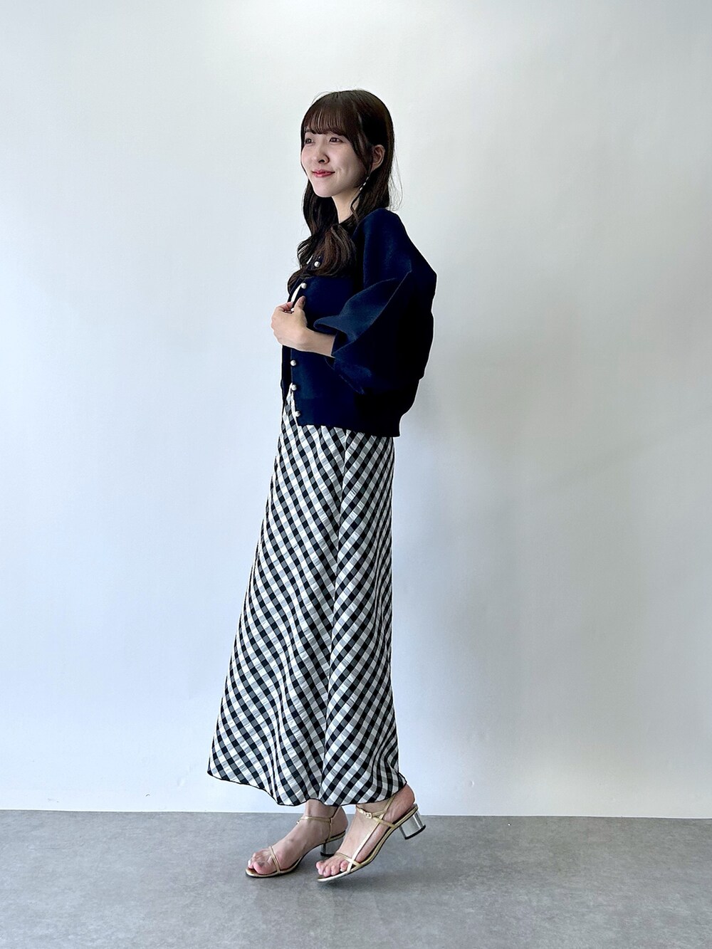 ブラック系のスカート、ブルー系のカーディガン/ボレロ、ホワイト系のタンクトップを着用したレディースの夏コーディネートの2枚目の写真