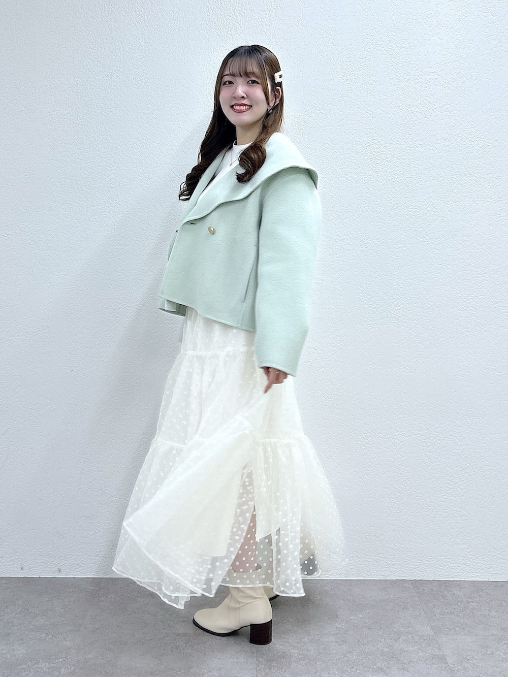 グリーン系のその他アウター、ホワイト系のニット/セーター、ホワイト系のスカートを着用したレディースの秋コーディネートの4枚目の写真