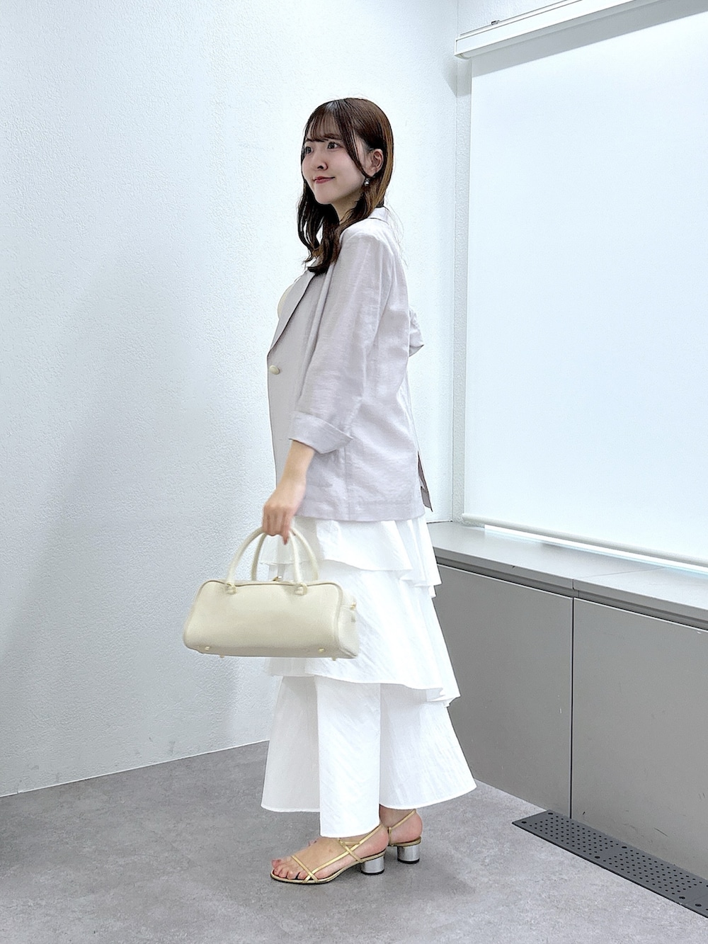 ベージュ系のニット/セーター、ベージュ系のテーラードジャケット、ホワイト系のスカートを着用したレディースの春コーディネートの3枚目の写真