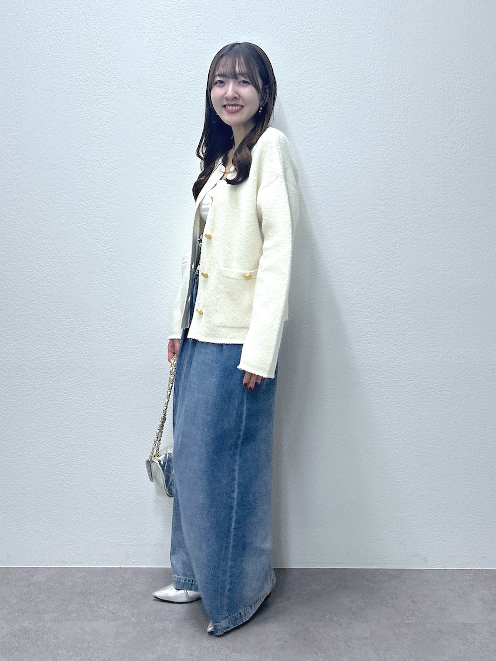 ホワイト系のノーカラージャケット、ブルー系のデニムパンツ、ホワイト系のキャミソールを着用したレディースの秋コーディネートの2枚目の写真