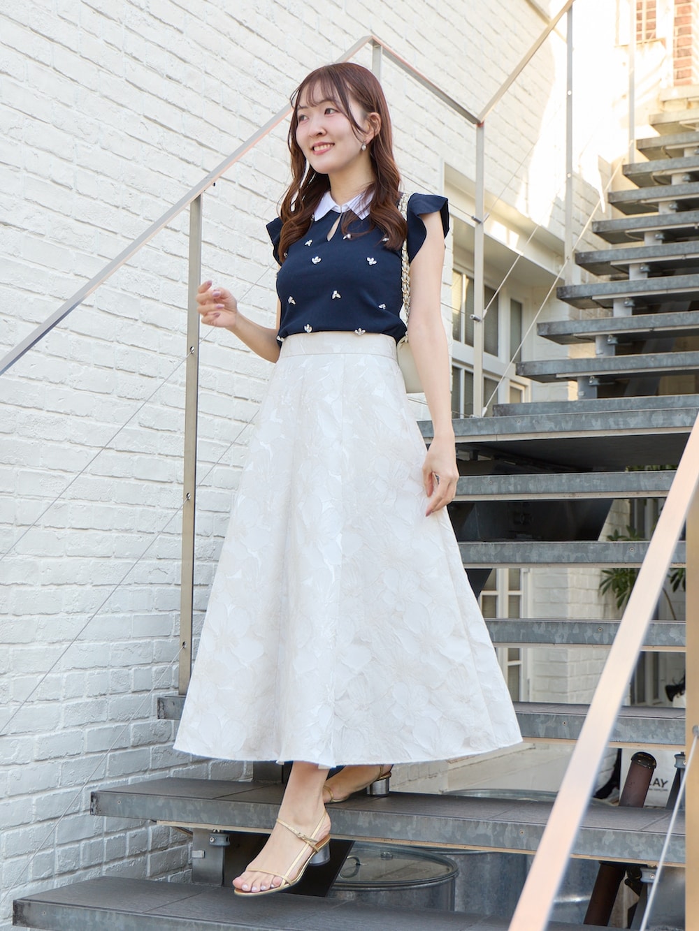 ブルー系のニット/セーター、ホワイト系のスカートを着用したレディースの春コーディネートの2枚目の写真