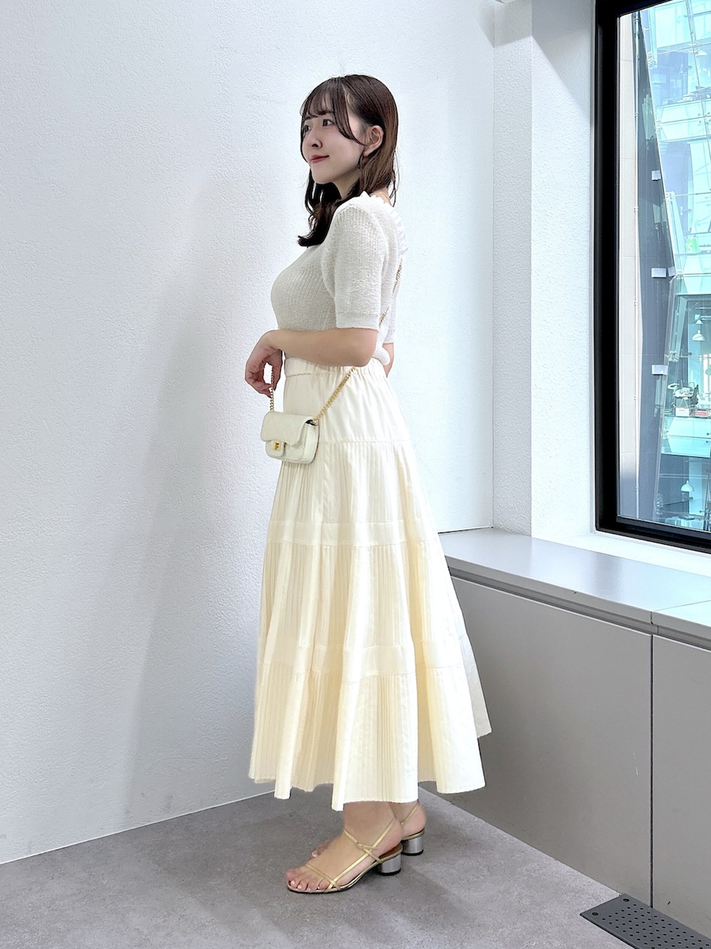 ベージュ系のニット/セーター、ホワイト系のスカートを着用したレディースの春コーディネートの2枚目の写真