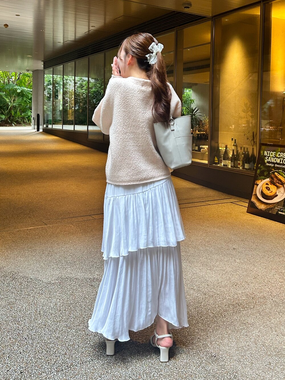 ピンク系のノーカラージャケット、ホワイト系のスカート、ホワイト系のサンダルを着用したレディースの秋コーディネートの3枚目の写真