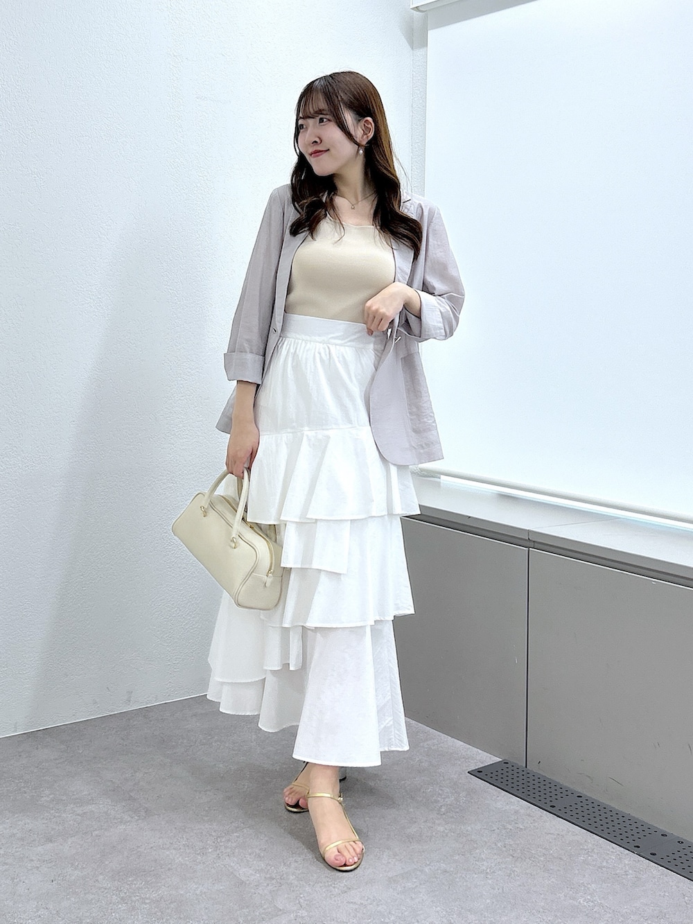 ベージュ系のニット/セーター、ベージュ系のテーラードジャケット、ホワイト系のスカートを着用したレディースの春コーディネートの2枚目の写真