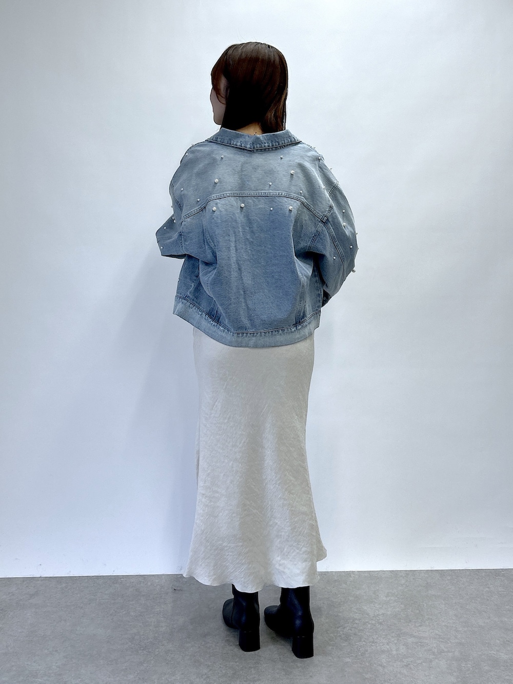 ブルー系のデニムジャケット、ブルー系のニット/セーター、グレー系のスカートを着用したレディースの秋コーディネートの4枚目の写真