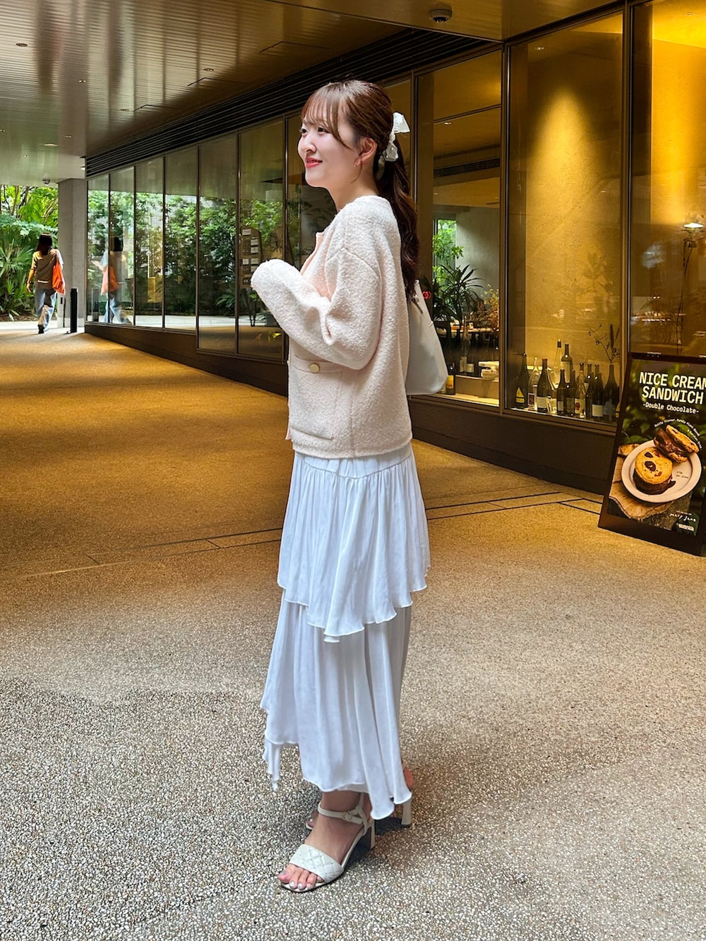 ピンク系のノーカラージャケット、ホワイト系のスカート、ホワイト系のサンダルを着用したレディースの秋コーディネートの2枚目の写真