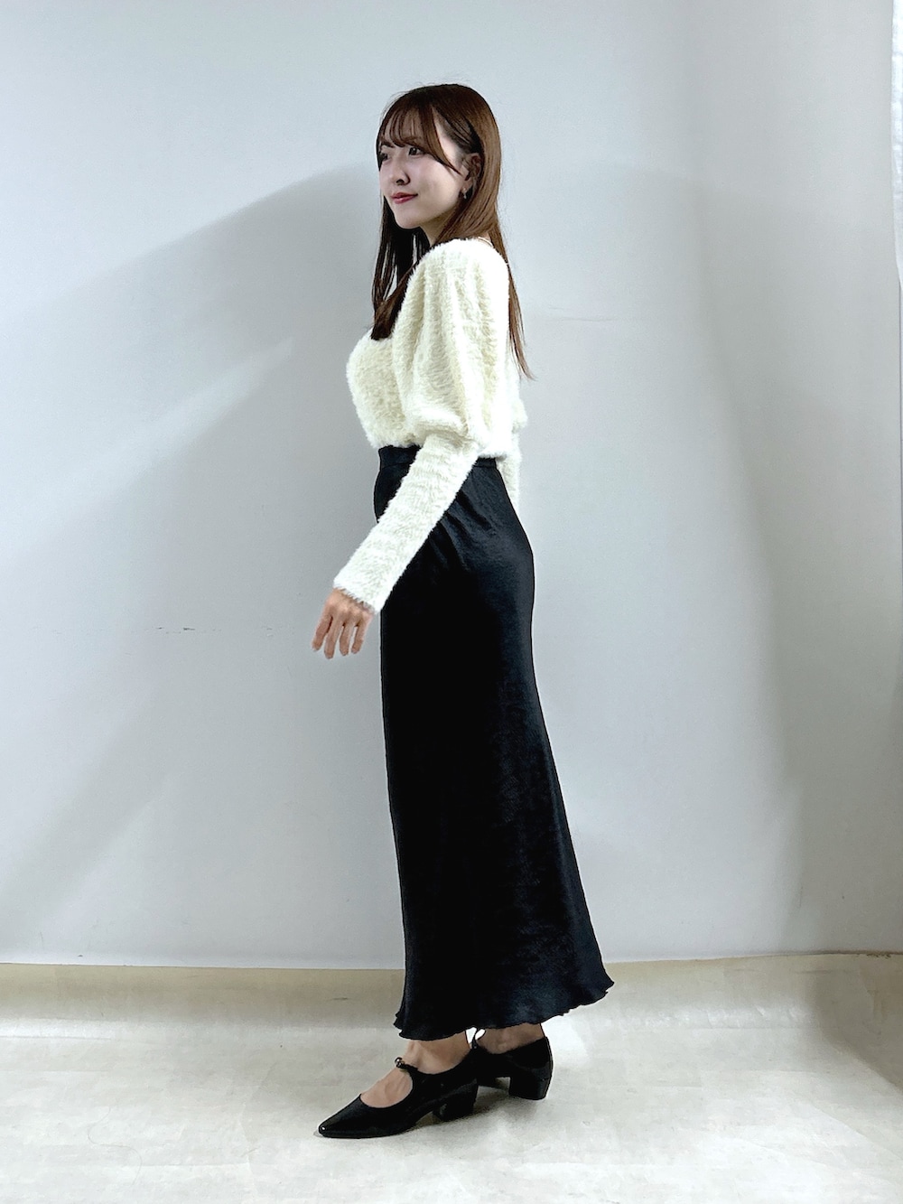 ホワイト系のニット/セーター、ブラック系のスカートを着用したレディースの秋コーディネートの2枚目の写真