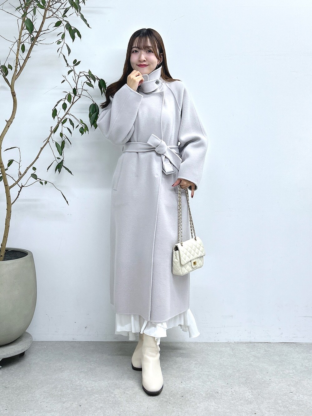 グレー系のステンカラーコート、ホワイト系のスカートを着用したレディースの秋コーディネートの2枚目の写真
