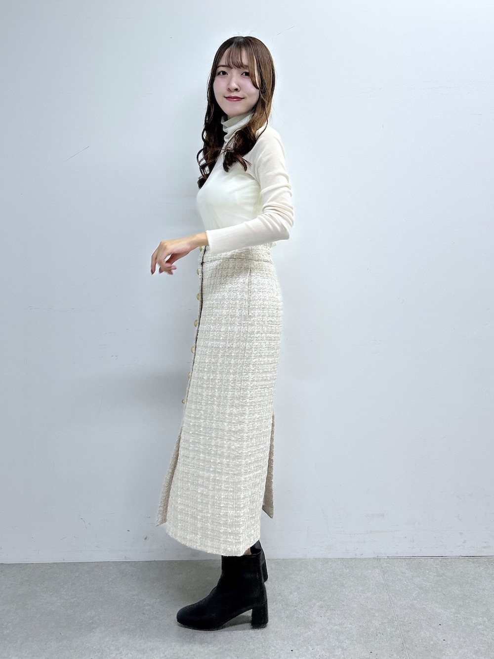 ホワイト系のTシャツ/カットソー、ベージュ系のスカート、ブラック系のブーツを着用したレディースの秋コーディネートの2枚目の写真