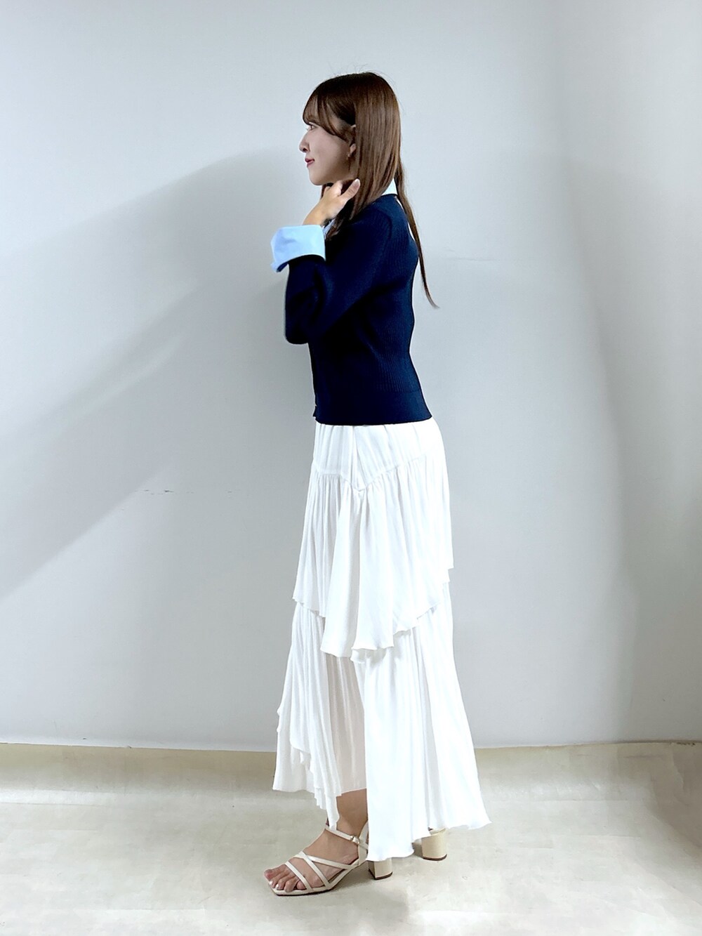ブルー系のニット/セーター、ホワイト系のスカートを着用したレディースの秋コーディネートの2枚目の写真