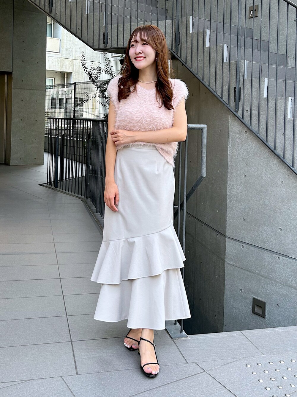 ピンク系のベスト、ベージュ系のスカートを着用したレディースの夏コーディネートの4枚目の写真