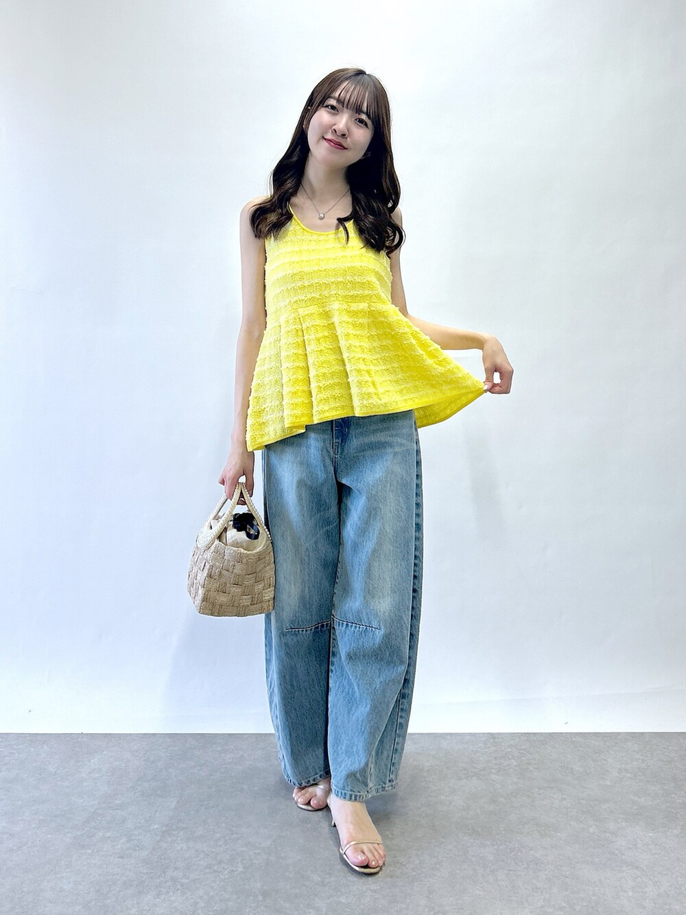 イエロー系のベスト、ベージュ系のトートバッグ、ブルー系のデニムパンツを着用したレディースの春コーディネートの4枚目の写真