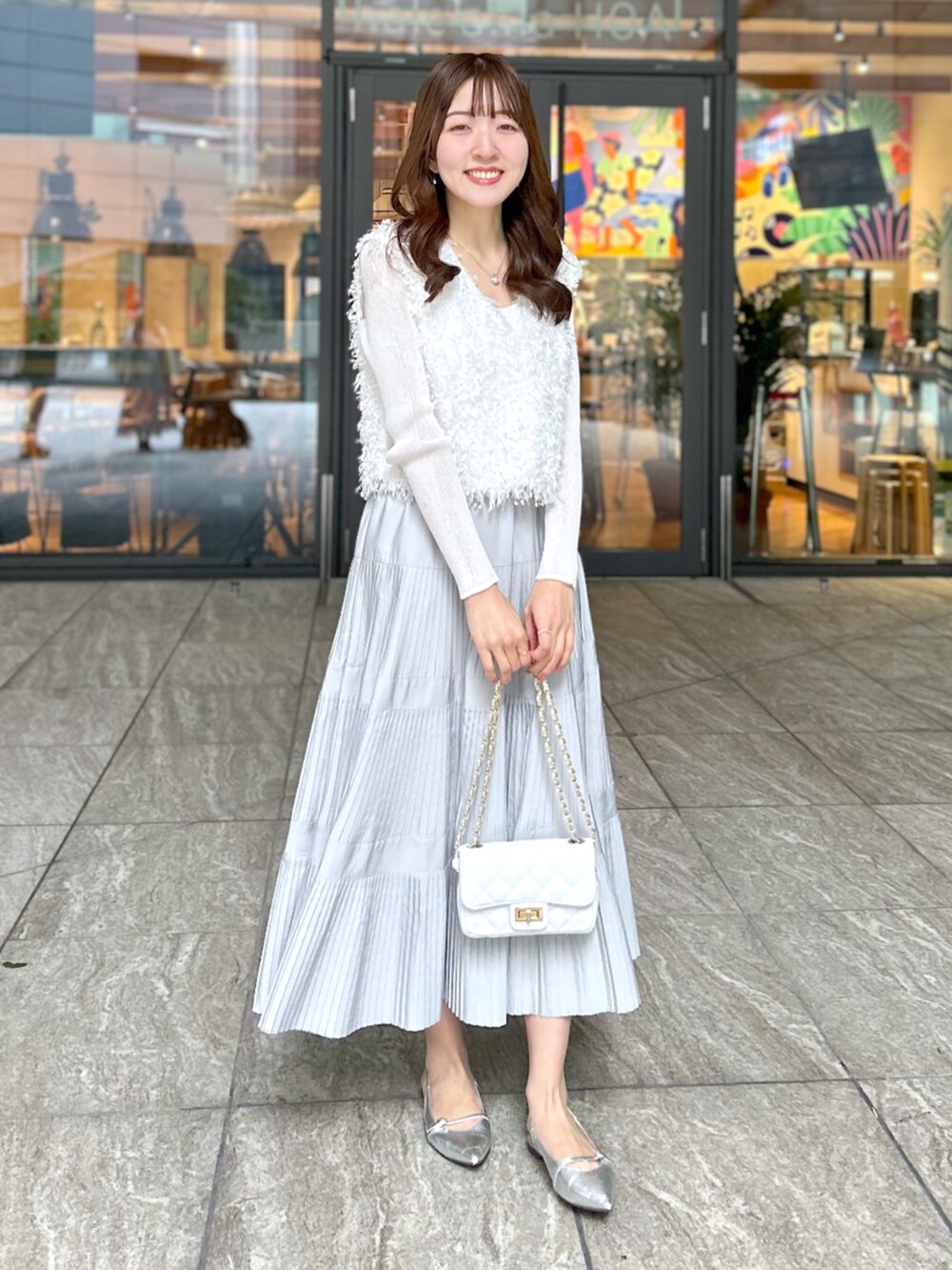 ホワイト系のシャツ/ブラウス、グレー系のスカート、ホワイト系のニット/セーターを着用したレディースの春コーディネートの5枚目の写真