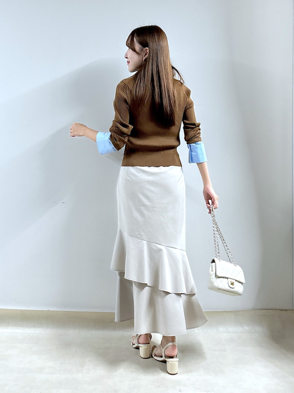 ブラウン系のニット/セーター、ベージュ系のスカートを着用したレディースの秋コーディネートの3枚目の写真