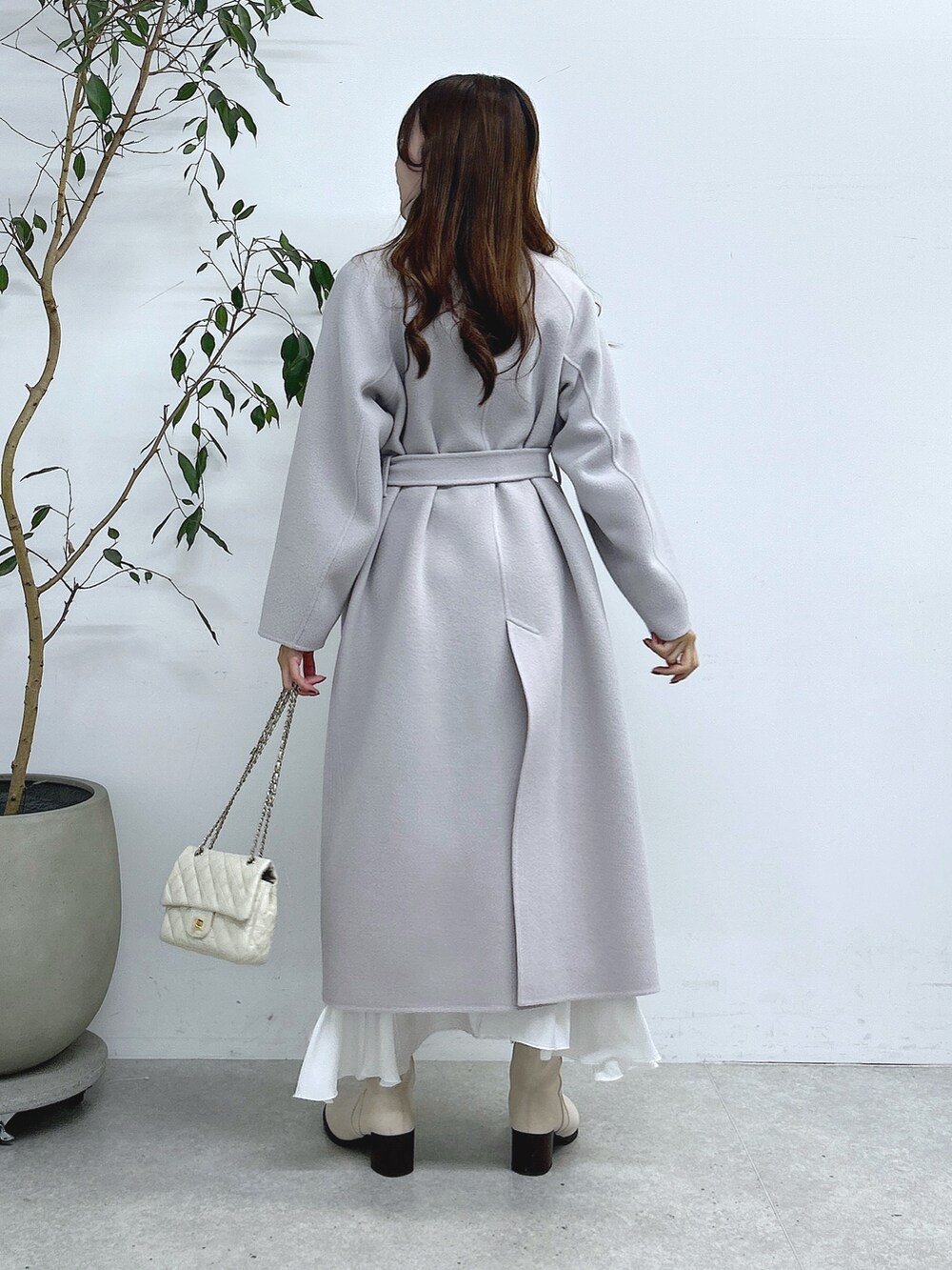 グレー系のステンカラーコート、ホワイト系のスカートを着用したレディースの秋コーディネートの5枚目の写真